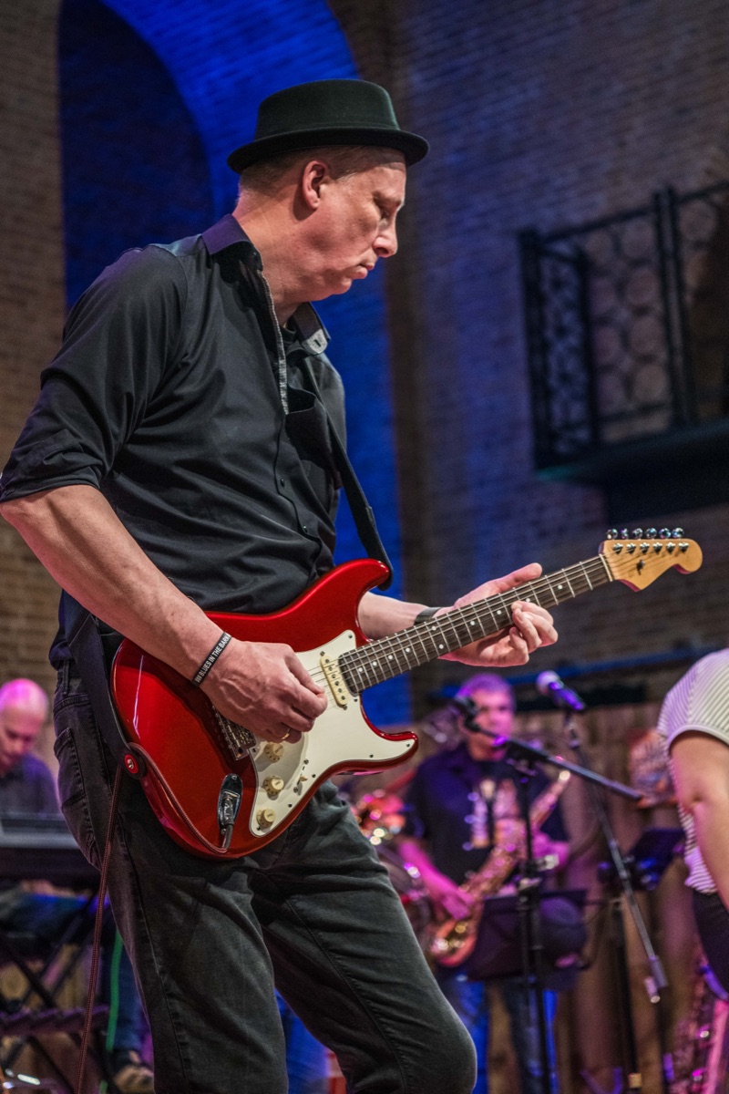 Gitarist met rode gitaar in blauw podiumlicht